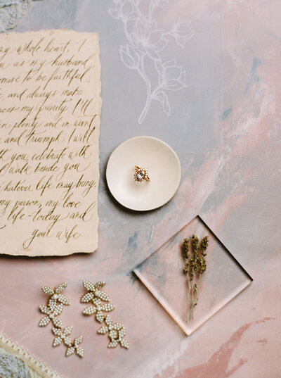 Halo engagement ring with petal shaped earrings and calligraphed vows on handmade paper