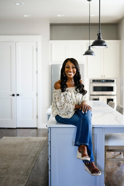 Deme Riley sitting on a kitchen island, introducing herself as a transformational life coach for women.
