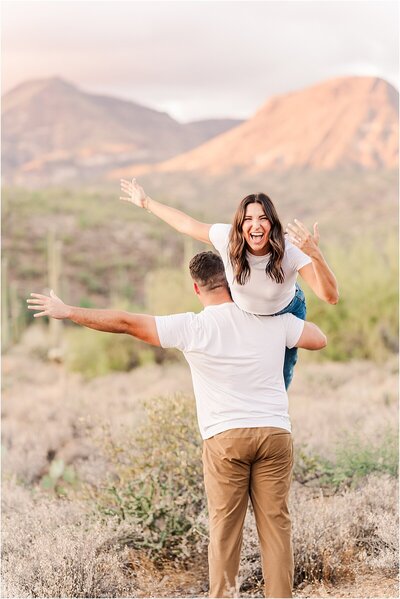 Newly engaged couple showing off engagement ring at sunset