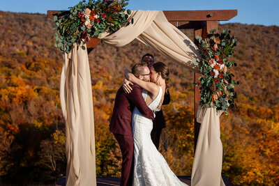 Bride and groom sharing their first kiss during wedding ceremony at Cranmore Mountain Summit in North Conway NH