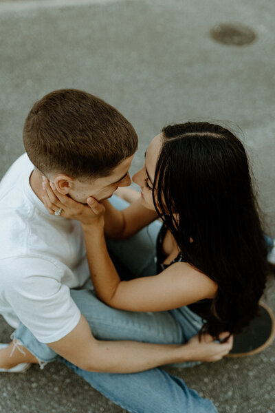 L stradling J on a skateboard, holding J's face about to kiss each other