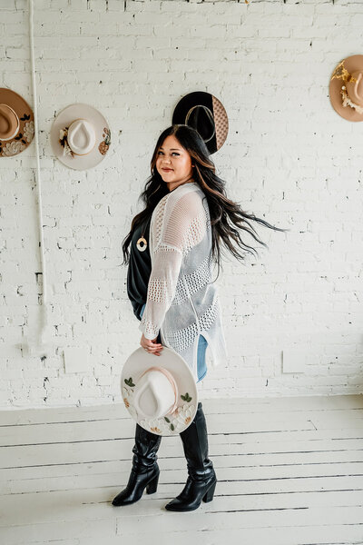 a woman holding a hat she created  in a branding shoot for her hat company