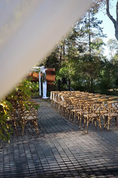 Outdoor courtyard ceremony setup with rows of chairs and an aisle in the gardens at Ashlar.