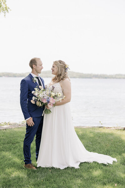 Groom and Bride stand in front of a lake