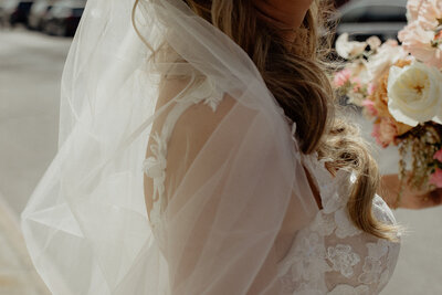 Bride with flowing veil holding pastel floral bouquet