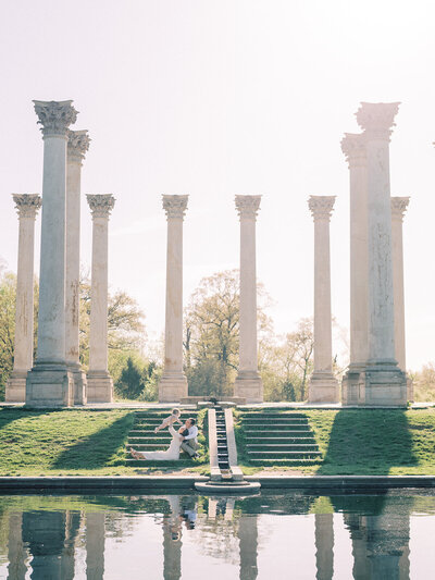 A young family sits on the steps of the Capital Columns at the National Arboretum.