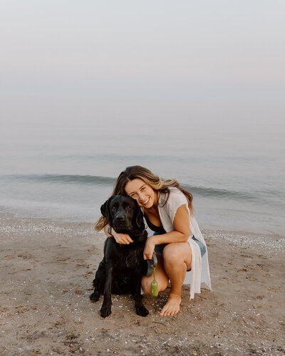 A photo of a girl and her black labrador on the beach in Cobourg.