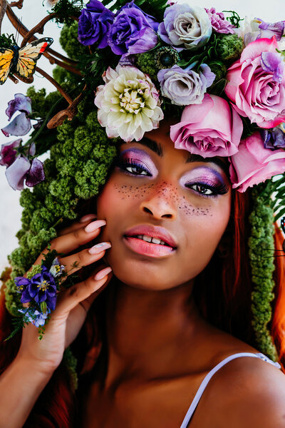 a beautiful black woman, with a stunning flower headdress on her head looking straight into the camera