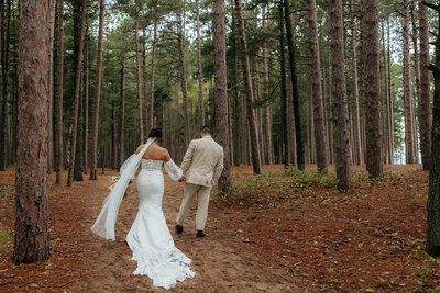 wedding couple walking through the woods in their wedding attire