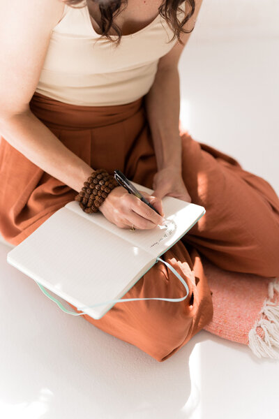 A woman is writing in her journal, expressing her thoughts about the transformational power of self love