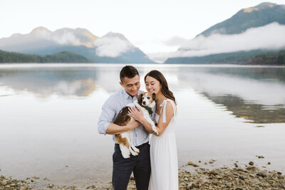 a couple standing together holding their dog in front of the view at Alouette Lake in Golden Ears Provincial Park