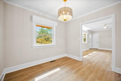 Light filled room with hardwood floors, large window, and hanging light fixture.