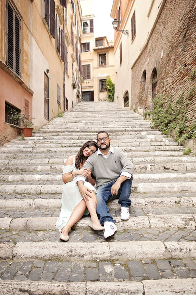 A couple sitting on an old roman staircase with her head on his shoulder. Taken by Rome Photographer, Tricia Anne Photography.