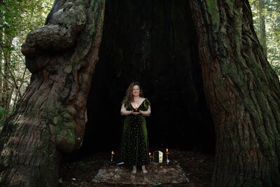 Spiritual CEO business coach Rachael Maddox, holding a candle in the forest, inviting you to join the CEO coven and ignite your business magick.