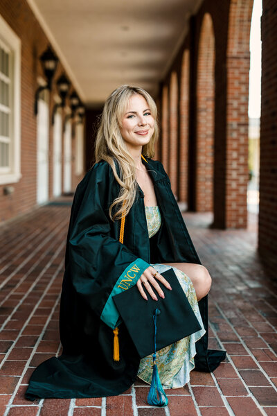 Proud UNCW senior in cap and gown on campus, Wilmington college graduation photography
