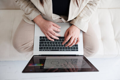 Hands typing on a laptop with a digital design displayed on a tablet – creating bold brand designs for women entrepreneurs