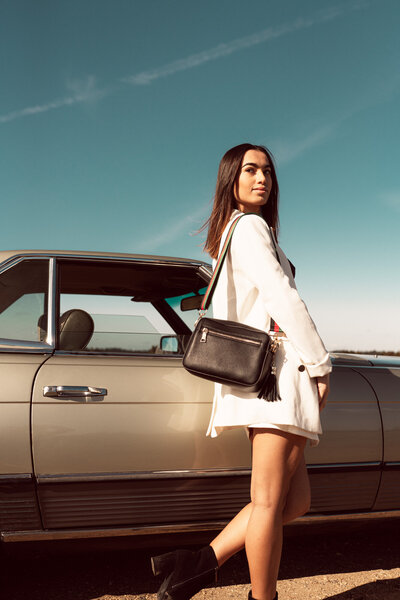 olive green wall with tropical leaf batten wall paper in bathroom with sink and round mirror