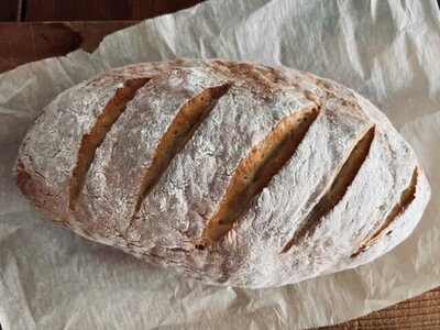 A rustic loaf of freshly baked bread on a wooden cutting board, showcasing the handcrafted baked goods available at Sleeping Dog Plants.