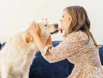 Golden retriever licking a woman’s face while she scrunches her face in a home in downtown Ann Arbor during a board and train session
