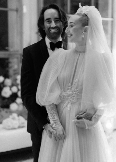 A bride and groom smile as they pose for portraits on their autumnal wedding day in London.