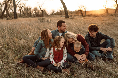 family of six sitting in a field laughing