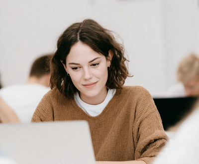 Sally David smiling at her laptop during brand voice session, testimonial image for Jasmina Kimova’s branding transformation services