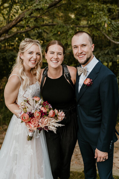 couple smiling with photographer at wedding