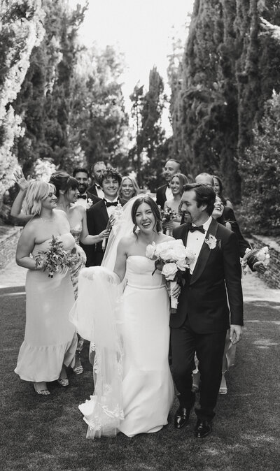 bride and groom smiling an walking with wedding party