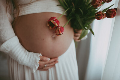 pregnant maternity mom holds belly with flowers