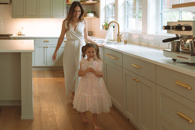 female wearing white pantsuit behind daughter in traditional at home kitchen