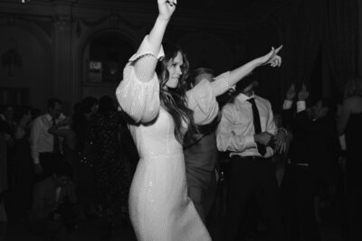 Bride dancing with arms in the air at wedding reception