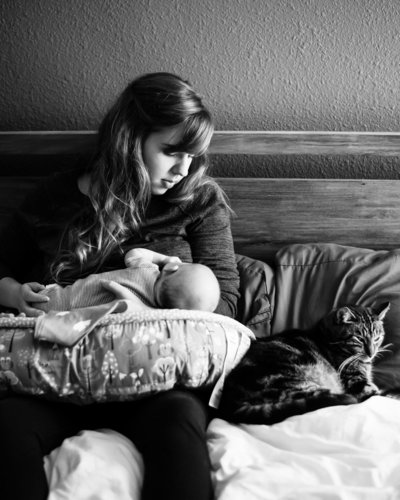 Breastfeeding mother in bed along side cat