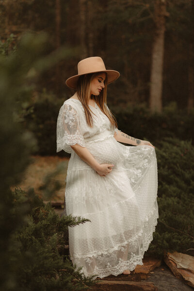 Pregnant woman in boho white dress with a hat by Atlanta Maternity Photographer