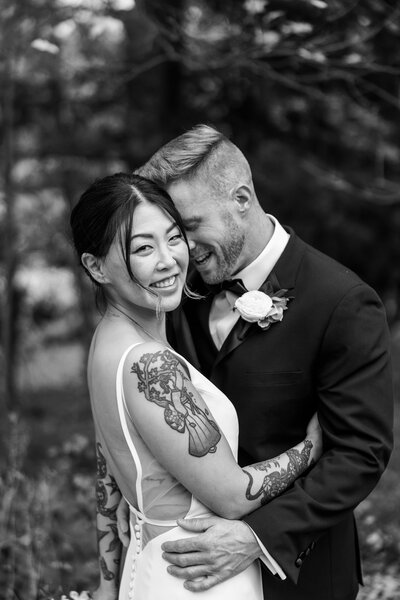 Black and white image of bride and groom with their heads together and arms around each other