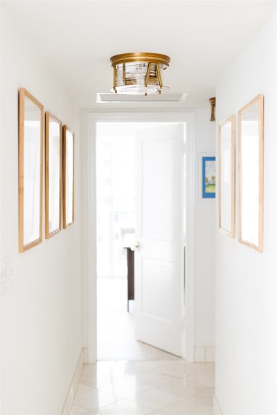 White hallway with gold frames and lighting