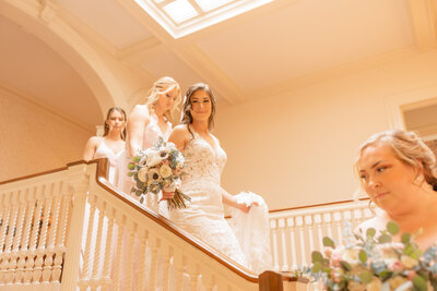 Liriodendron Mansion Wedding Photographer takes a photo of the bridal party coming down the mansion stairs of the Liriodendron mansion for cocktail hour