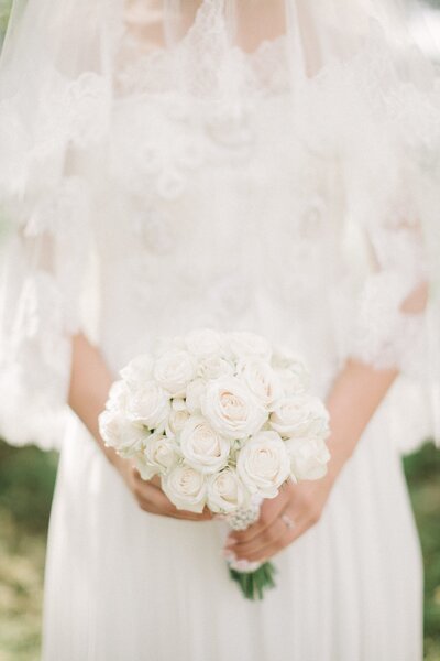 A bride holding a white bouquet on her wedding day.
