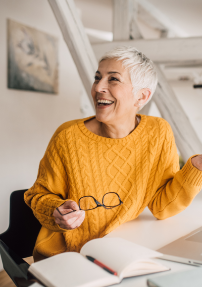 An older woman laughing in a yellow jumper