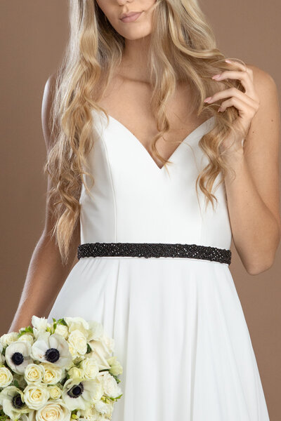 Bride wearing a black rhinestone belt and holding a black and white bouquet