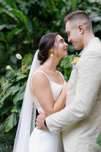 A newlywed couple standing close and smiling at each other 