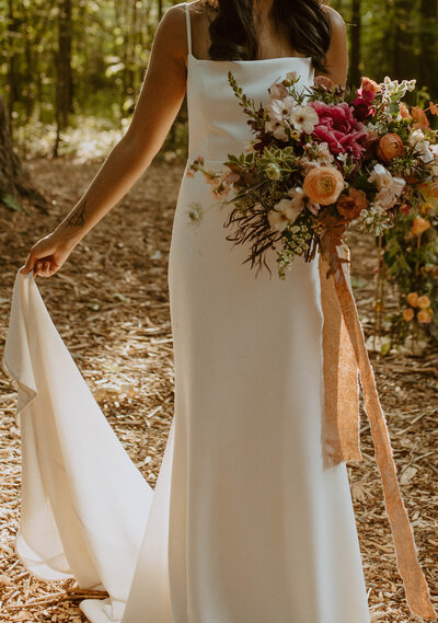 bride holding dress and flowers
