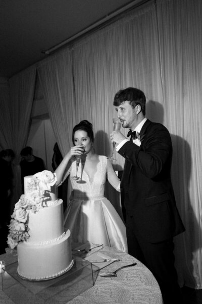 Bride and Groom sipping on Champagne after cutting their wedding cake during their reception in Atlanta, Georgia, photographed by Andrea-Marie Photography