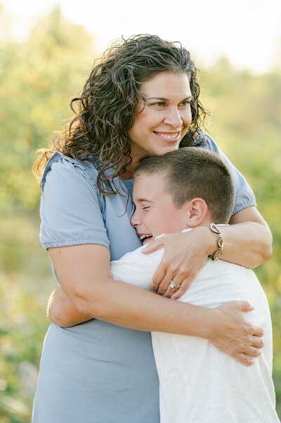 Mom hugs her older son into her chest and smiles off into the distance at a Milwaukee photo shoot.