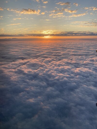 View from a plane of clouds as the sun sets.