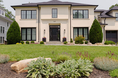Modern charming home with large windows and shrubs on clean neat yard with beautiful landscaping