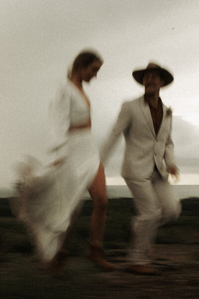 Joyful wedding party walking through open fields during a Sunshine Coast photography session with motion blur