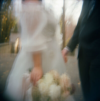Fashion-forward bride in dreamy film photo with bouquet on wedding day in dress