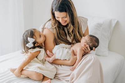 Newborn Photography in Madison Alabama by Whitney Briscoe - mom and daughter with newborn baby sitting on bed