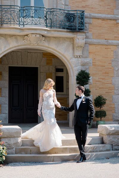 groom leading bride down the front steps of cairnwood estate