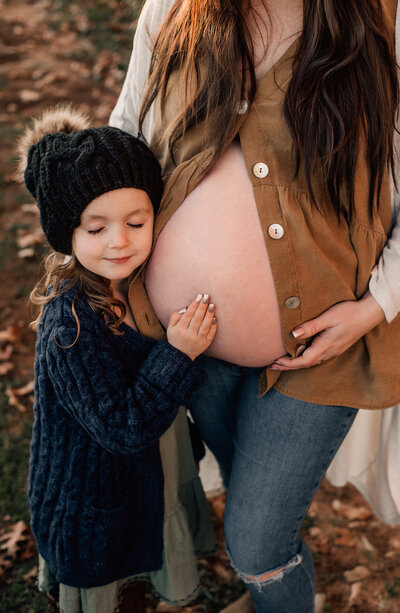 close up of girl holding her moms pregnant belly